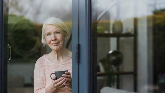 picture of senior woman at a glass window, to represent story about long-term care