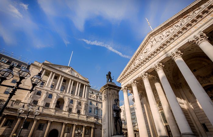 Low angle view of the main facades of the Bank of England and London Stock Exchange and the London Troops memorial at Bank Junction in the City of London. London.